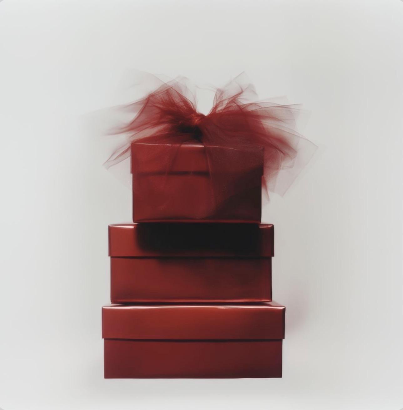Stacked deep-red gift boxes finished with red tulle