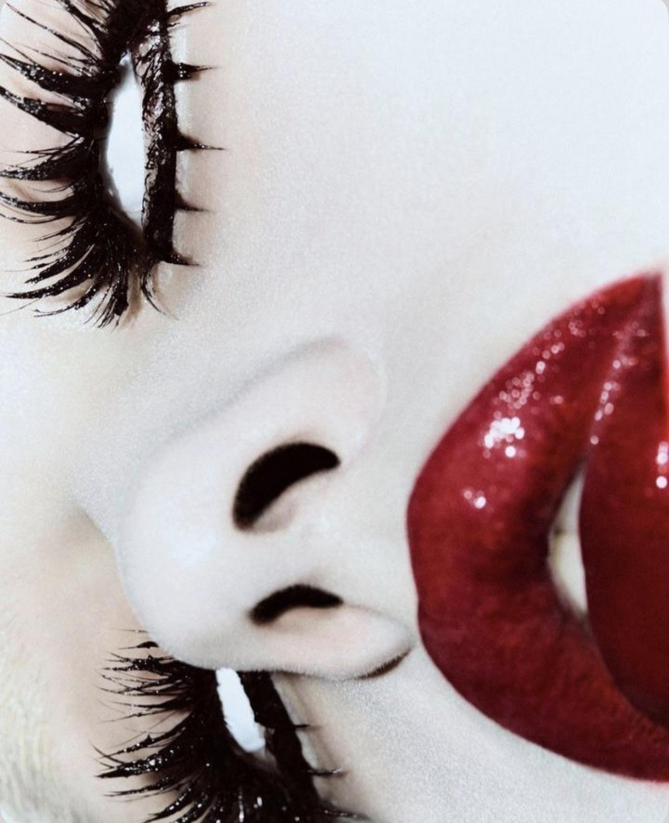 Close-up of a face with dramatic lashes and glossy deep-red lips